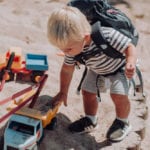 Junge spielt mit LKW im Sandkasten mit Beckmann Kindergarten Rucksack Modell 2020 fire truck