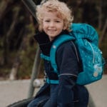 Junge sitzt auf Klettergerüst auf Spielplatz mit Beckmann Kindergarten Rucksack Modell 2020 Forest